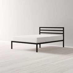 the bed frame is made from black wood and has a white mattress on one side