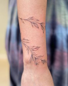 a person with a tattoo on their arm that has two leaves and one is not