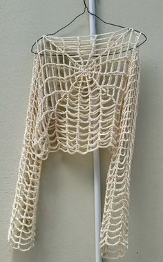 a crocheted crop top hanging on a clothes hanger