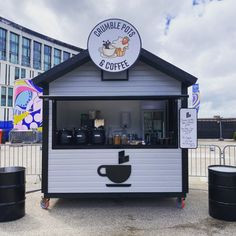 a small white and black building with a cup on the top that says tumble pot & coffee