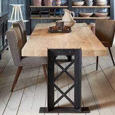 a wooden table surrounded by chairs and shelves