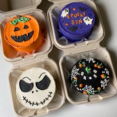 four decorated halloween cupcakes in plastic containers