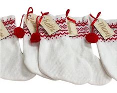 three pairs of white socks with red pom - poms hanging from the side