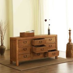 a wooden dresser sitting on top of a hard wood floor next to a vase filled with flowers