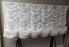 two black tripod lights are standing in front of a white drapeed curtain