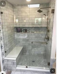 a walk in shower sitting next to a white tiled wall and floor with glass doors