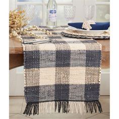 a plaid table runner with tassels and plates on the table next to it