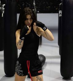 a woman standing in a boxing ring with her fist raised