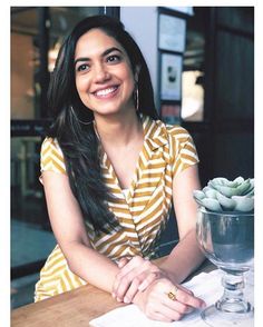 a woman sitting at a table smiling for the camera