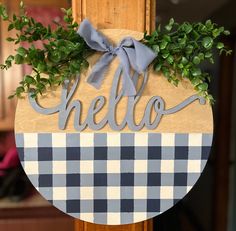 a wooden sign with the word hello painted on it and some green leaves around it