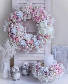 a wreath with pink and white flowers sitting on top of a table next to other decorations