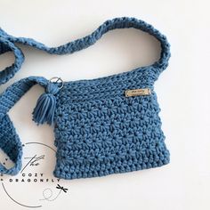 a crocheted purse with a tasseled strap and a tag on it