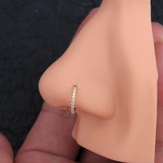 a close up of a person holding a fake nose with a diamond ring on it