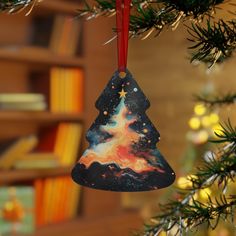 a christmas tree ornament hanging from a fir tree with bookshelves in the background