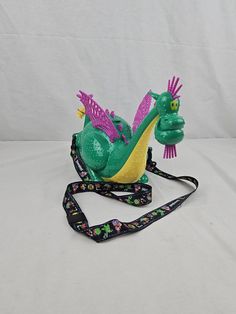 a green and purple toy sitting on top of a lanyard