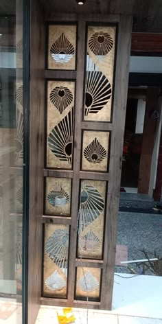 a wooden door with decorative designs on the side and glass doors to both sides, in front of a building