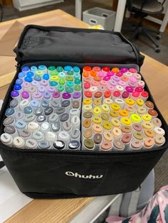 a black bag filled with lots of different colored buttons on top of a wooden table