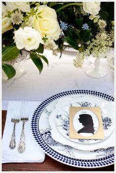 a table set with plates, silverware and flowers