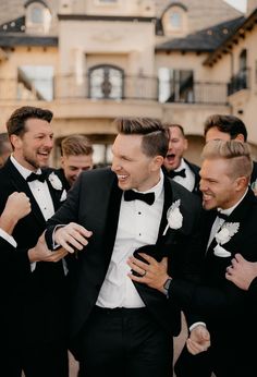 two men in tuxedos are hugging each other and laughing at the same time