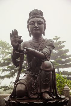 there is a buddha statue sitting in front of some trees