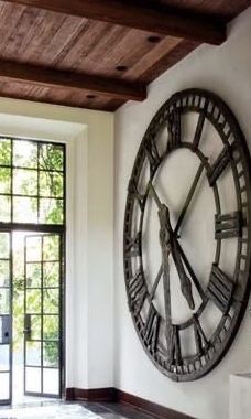 a large clock mounted to the side of a wall in a living room next to a window