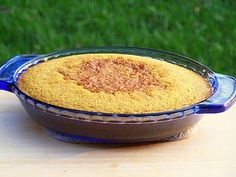 a blue glass dish filled with food sitting on top of a wooden table next to green grass