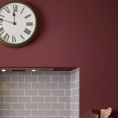 a clock mounted to the side of a brick wall next to a kitchen counter top