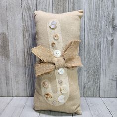 a decorative pillow with buttons and burlock on the front, sitting against a wooden wall