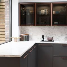 a kitchen with marble counter tops and wooden cabinetry next to a brick wall that has glass doors on it