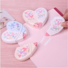 three heart shaped erasers sitting on top of a pink table next to a card