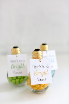 two small glass jars filled with yellow and green candies, one has a sign that says here's to bright future