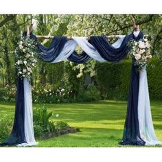 an outdoor wedding ceremony with blue and white draping, flowers and greenery