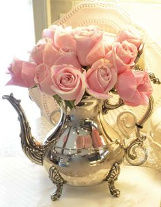 a silver tea pot with pink roses in it