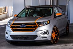 the front end of a silver and orange ford edge stripe car parked in a parking lot