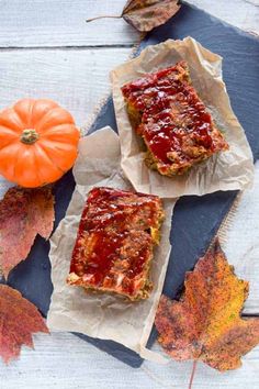 two pieces of meatloaf sitting on top of parchment paper next to an orange pumpkin