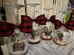 three glass vases with red and black bows on them sitting on a white table