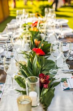 a long table is set with wine glasses and place settings for the guests to sit at