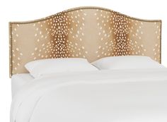 an upholstered headboard on a bed with white sheets