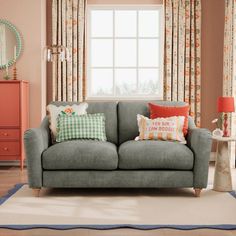 a living room scene with focus on the couch and pillows in front of the window