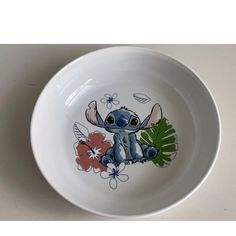 a bowl with an image of a baby elephant painted on the side and flowers around it