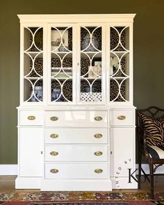 a white china cabinet sitting next to a chair