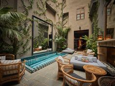 an indoor swimming pool surrounded by wicker furniture and potted plants in front of it