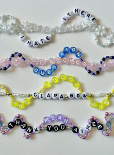 several bracelets with words written in different colors and shapes, all on a white surface