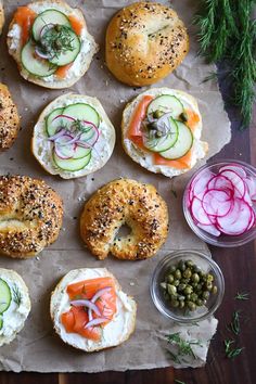 an assortment of bagels with cucumbers, salmon and capers on them