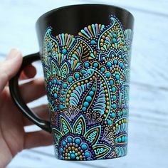 someone is holding a coffee cup with colorful designs on it