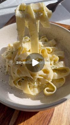 a white plate topped with pasta and cheese covered in sauce on top of a wooden table