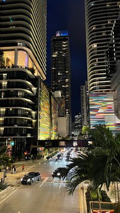 an empty city street at night with high rise buildings in the background and lights on