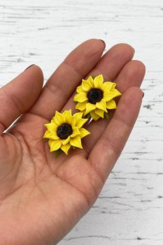 three yellow sunflowers sitting in the palm of someone's hand