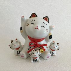 a white cat figurine with five small kittens on it's back