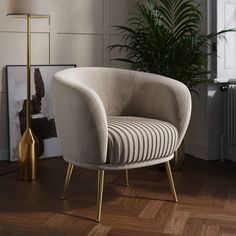 a chair sitting on top of a wooden floor next to a lamp and potted plant